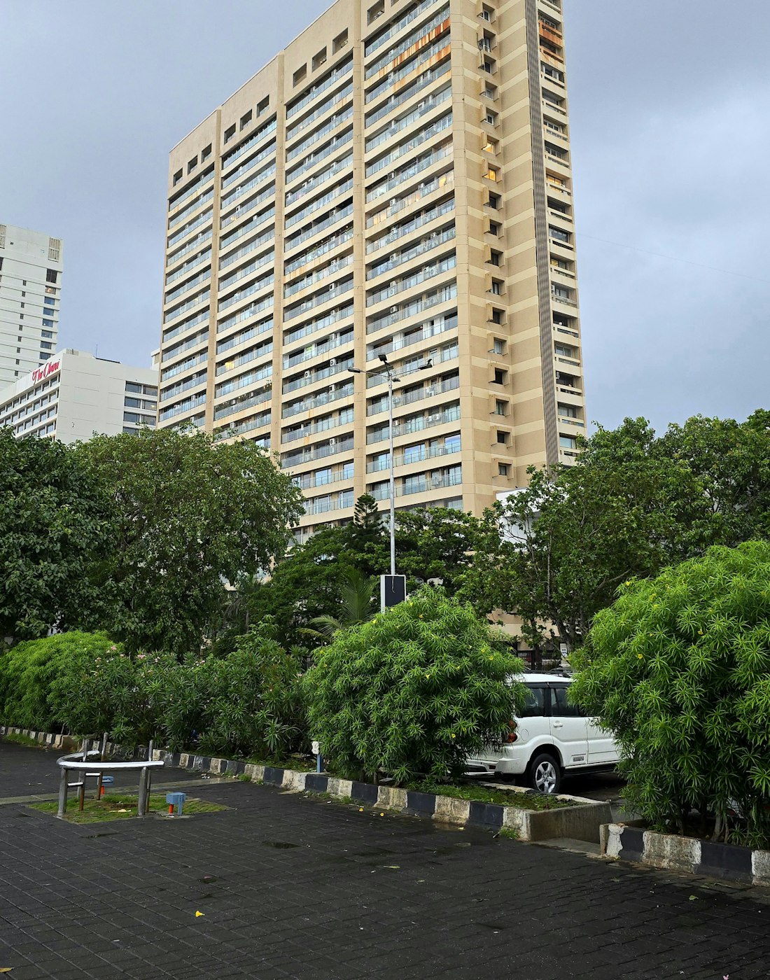 A residential tower rising above trees on a quiet city street