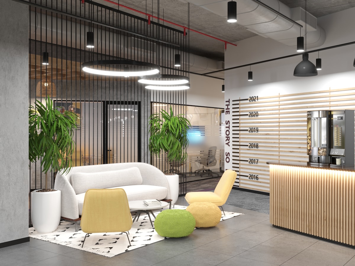 A reception lounge with a low sofa, plants and a timber front desk