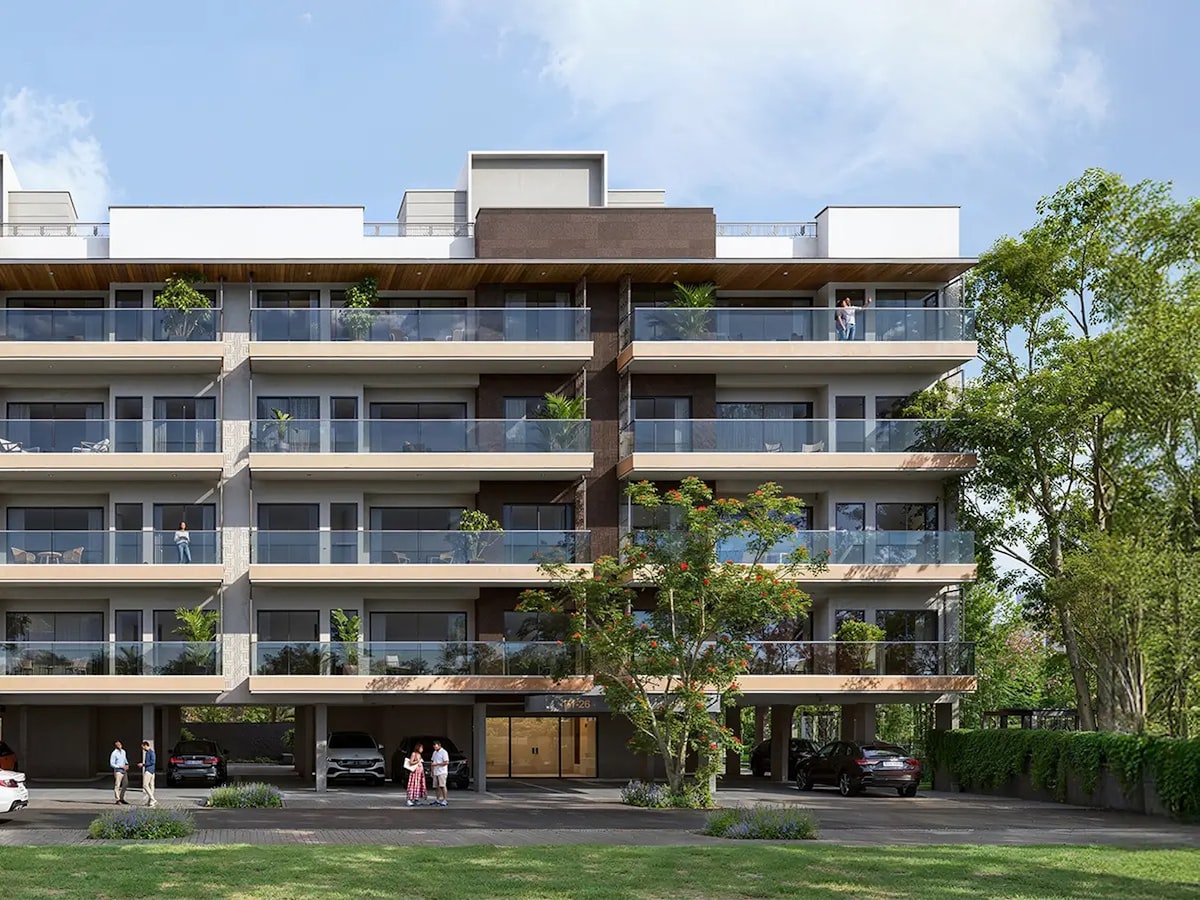 A low rise residential building with deep planted balconies, set back behind lawn