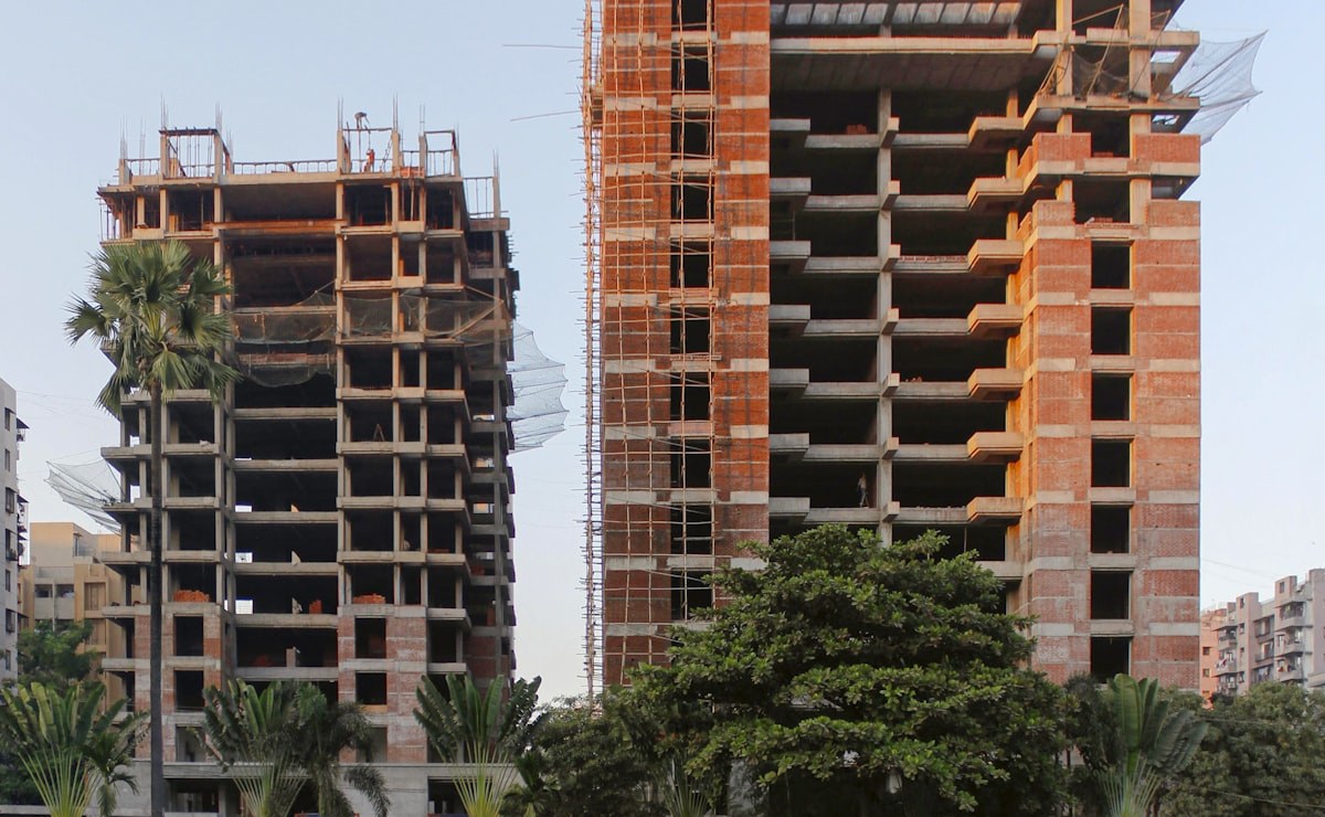 Two residential towers under construction, still in bare frame and brickwork