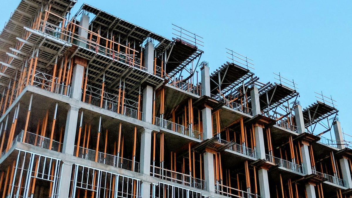 A concrete frame under construction, floor slabs propped and balconies not yet clad